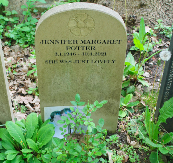 Headstone with plants and a photo tucked next to it. Reads: "Jennifer Margaret Potter / 3.1.1946 - 30.4.2021 / She was just lovely"