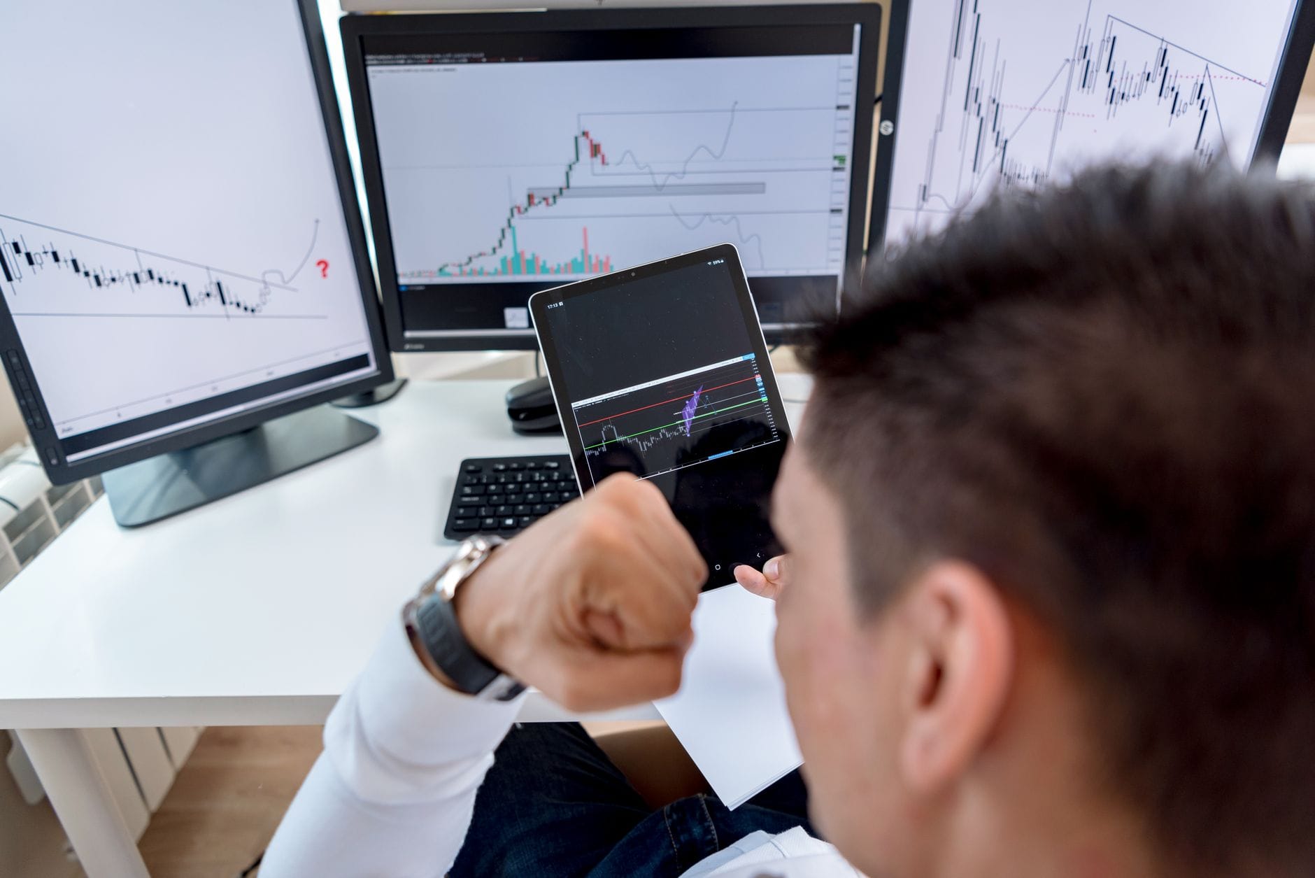 Focused trader reviewing cryptocurrency price charts and position sizing calculations on multiple monitors