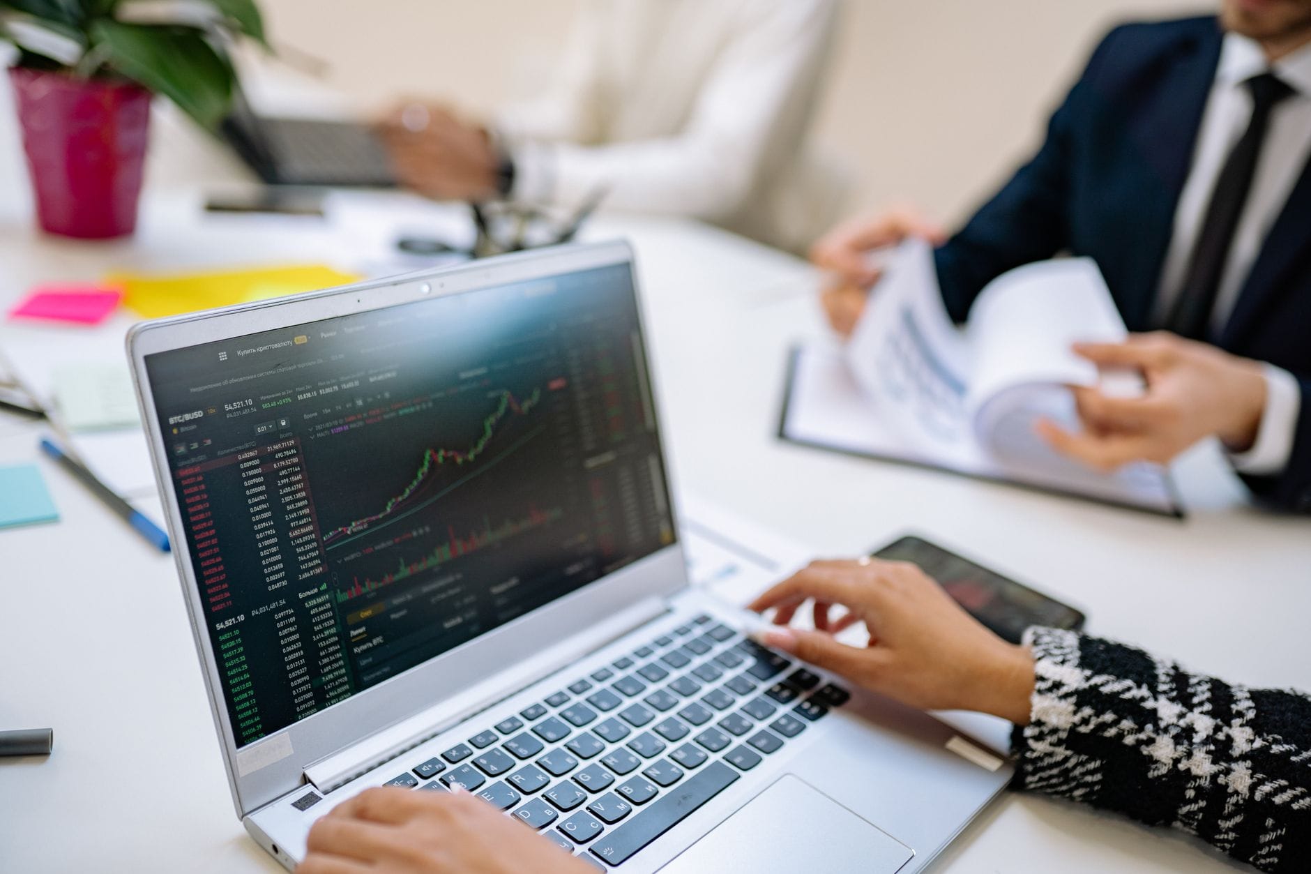 Investors examining cryptocurrency launchpad platforms on laptop screens in modern office