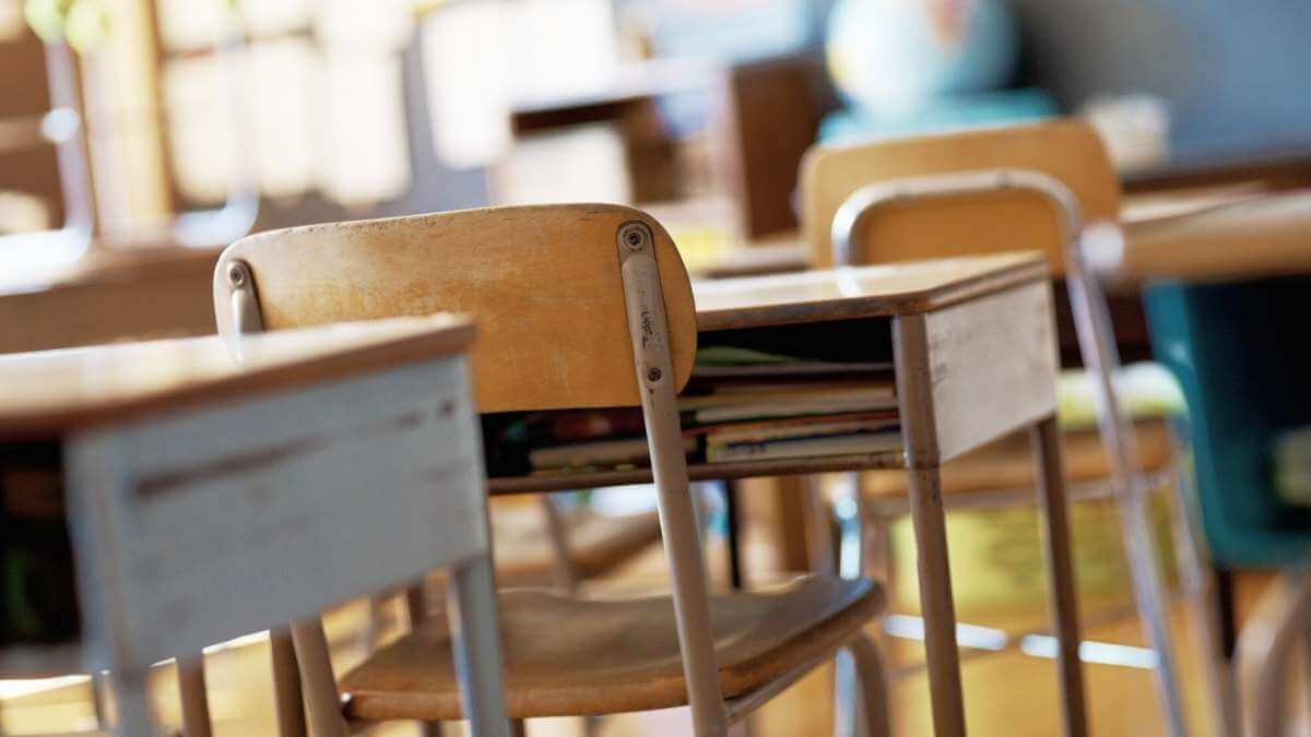 The inside of a classroom with old, retro-style desks and chairs.