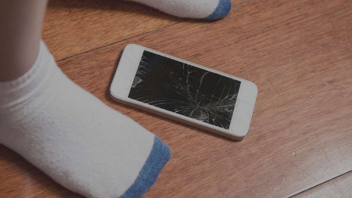 A male escort client has dropped his phone and it is lying on the floor with a cracked screen.