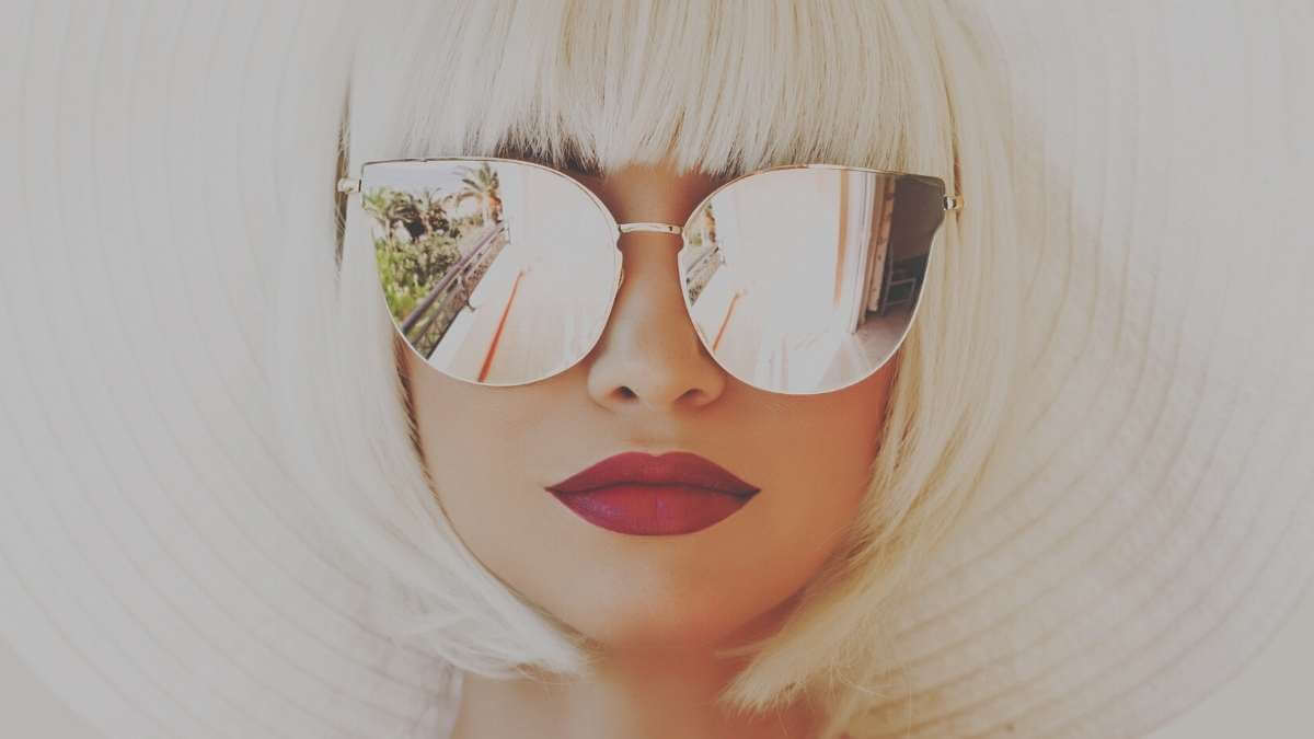 A female Las Vegas escort wearing large sunglasses and red lipstick.