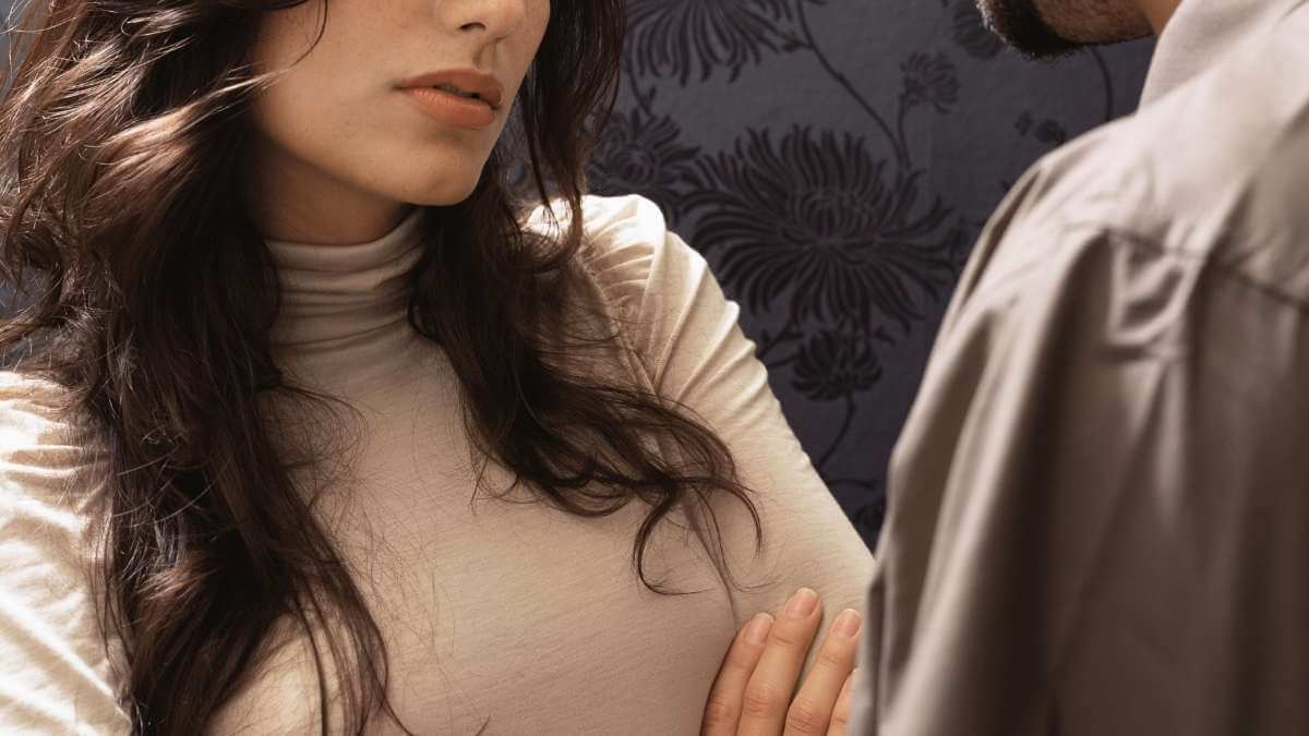 A woman crosses her arms while talking to a man with a beard