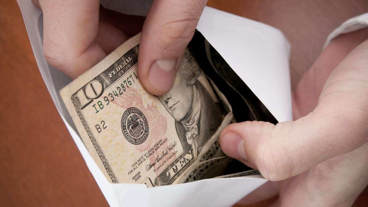 Closeup: An escort client pays their provider with cash in an envelope.