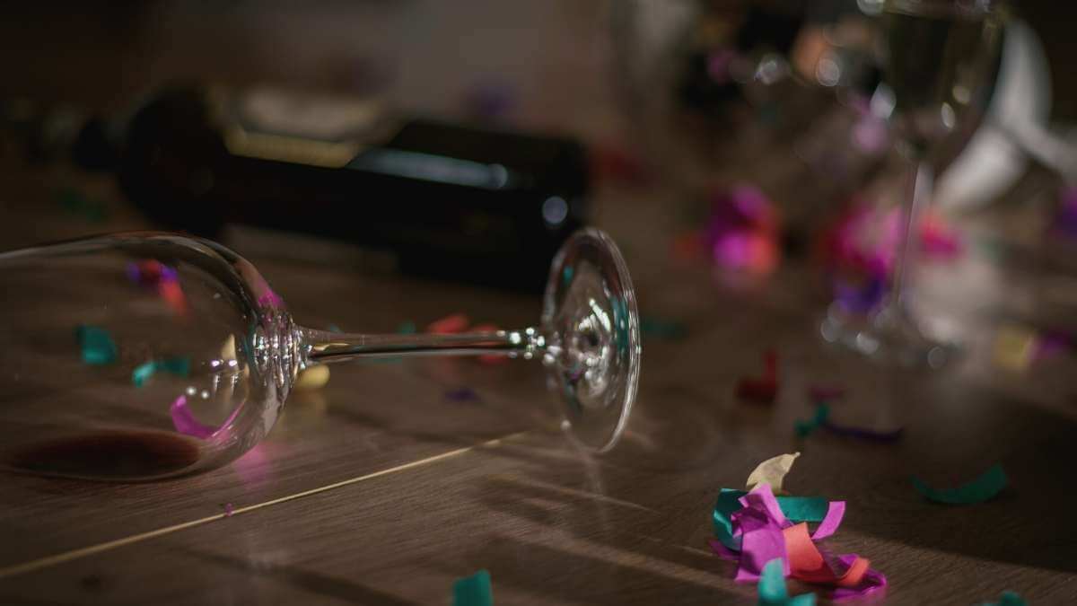 A wine glass and wine bottle tipped over on the floor after an escort booking.