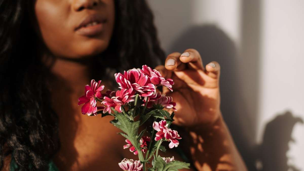 A female escort in her twenties holds a boquet of wildflowers.