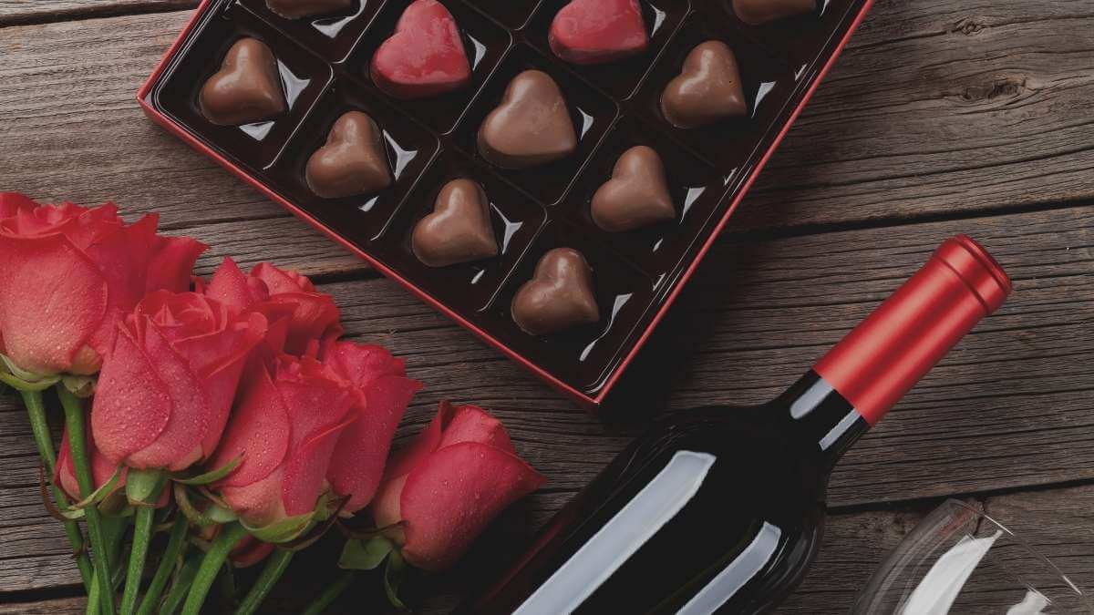 An escort client's presents for his date: wine, flowers, and chocolates.