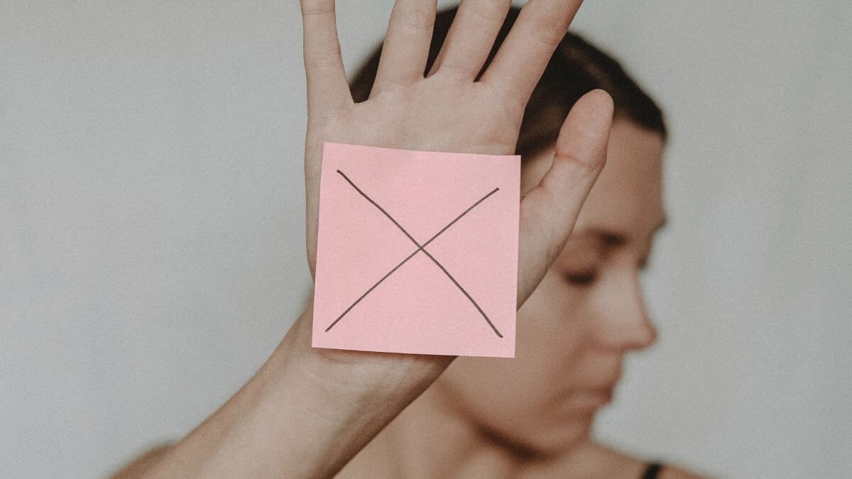 A female escort looks away and holds up a post-it note with an 'x' written on it.