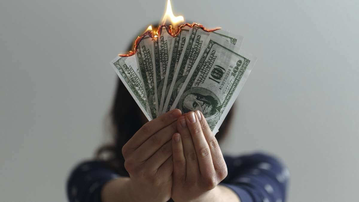A female escort holds up United States dollar bills that are on fire.