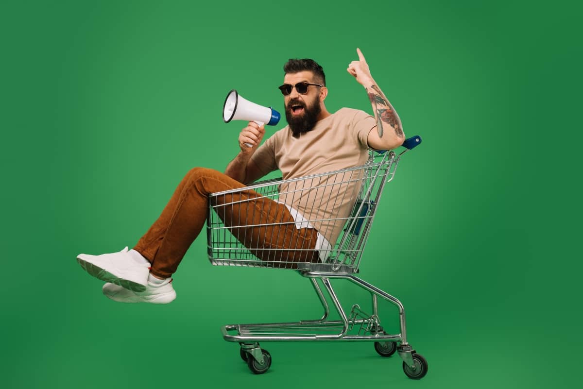 brand awareness - man with a bullhorn sitting in a shopping cart