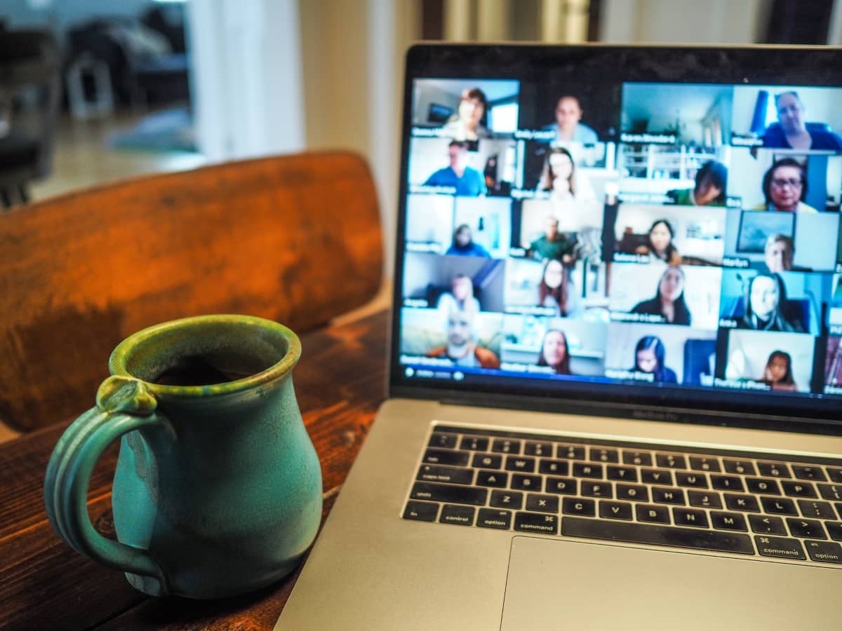 online training software - laptop with learners on the screen and coffe cup beside the laptop