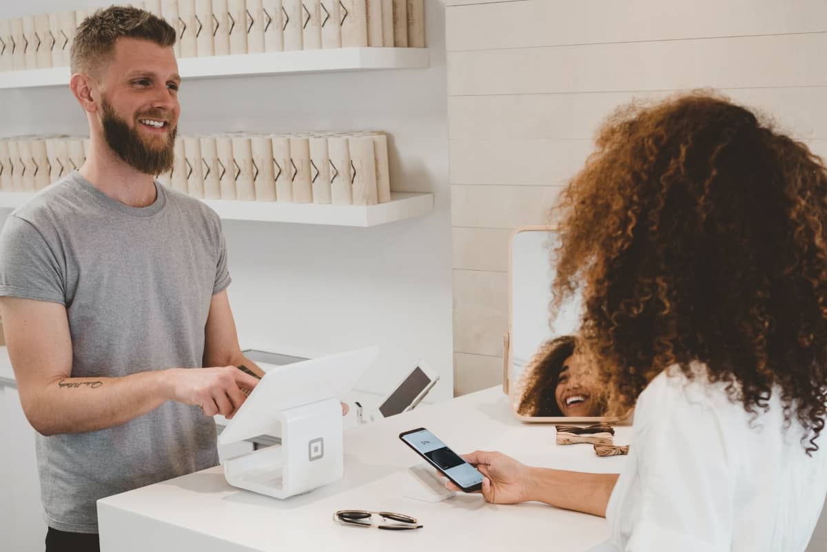 ecommerce sales funnel - smiling woman at checkout register with smiling sales person