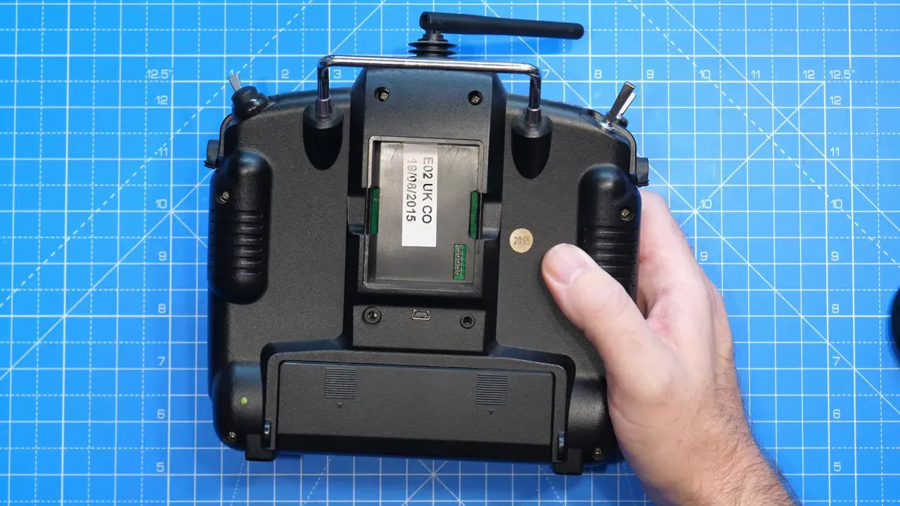 Top-down rear view of a FrSky Taranis showing the open JR module bay clearly on a blue cutting mat