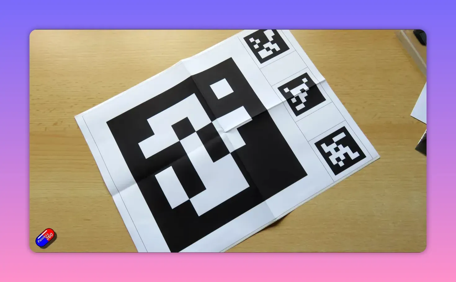 Printable AprilTag landing target on a wooden surface, large central tag and three smaller tags visible