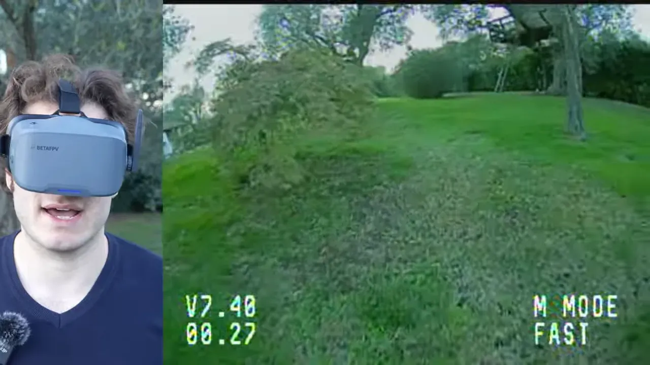 FPV forward view over a grassy slope in M Mode Fast with presenter wearing VR04 goggles visible at the side
