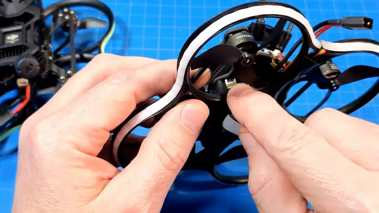 Close-up of hands pointing at the motor plug connector on a Pavo20 Pro II micro drone.