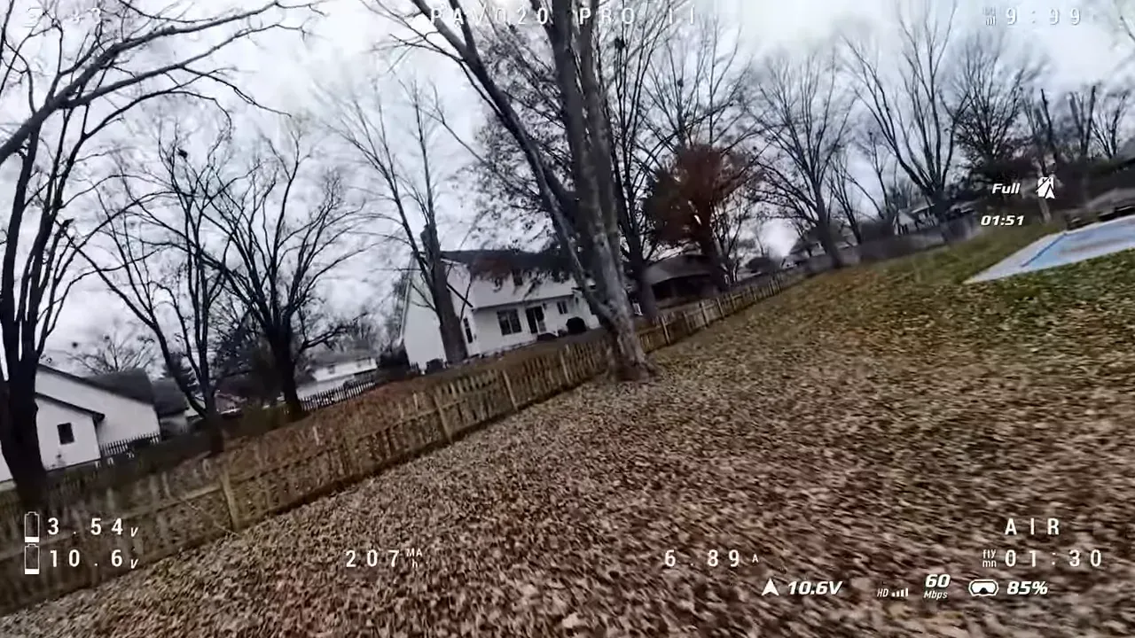 Tilted FPV view over a leaf-covered yard with a wooden fence, pool and neighbouring houses; PAVO20 PRO II telemetry visible