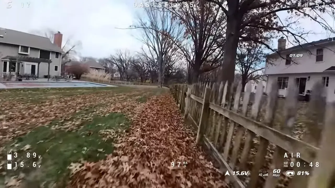 OasisFly35 FPV wide shot of a backyard with fallen leaves, wooden fence, trees and houses during a winter flight