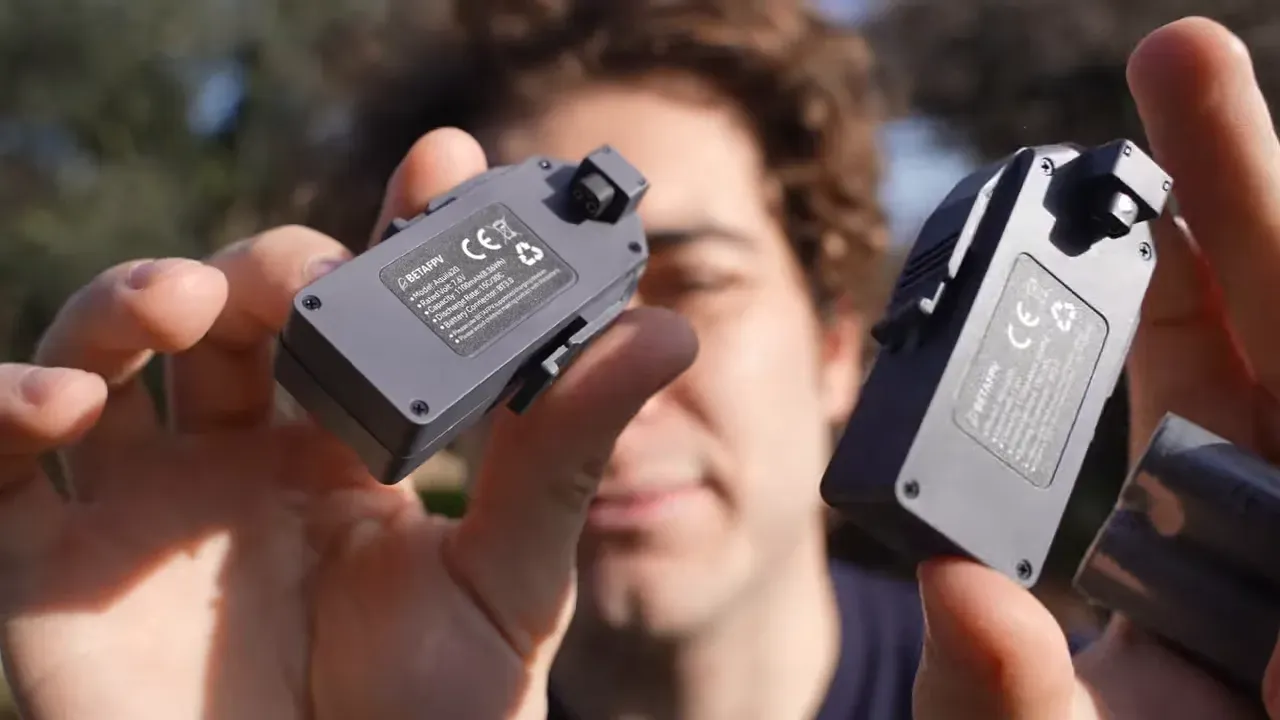 two gray Aquila20 HD modules held close to the camera showing the product label, presenter blurred behind