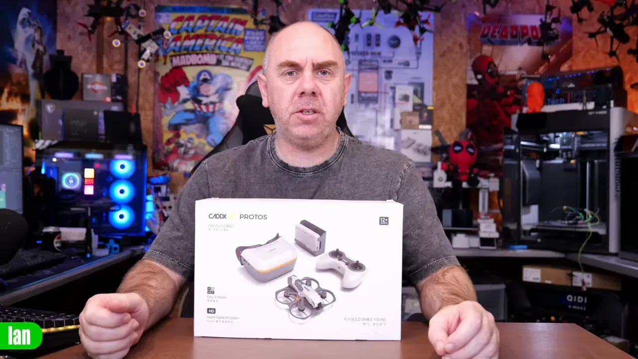 Presenter holding a Caddx Protos product box on a desk with workshop background