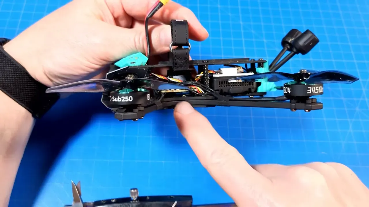 Close side view of OasisFly35 showing split carbon arms, two-plate sandwich construction and cable routing with finger pointing