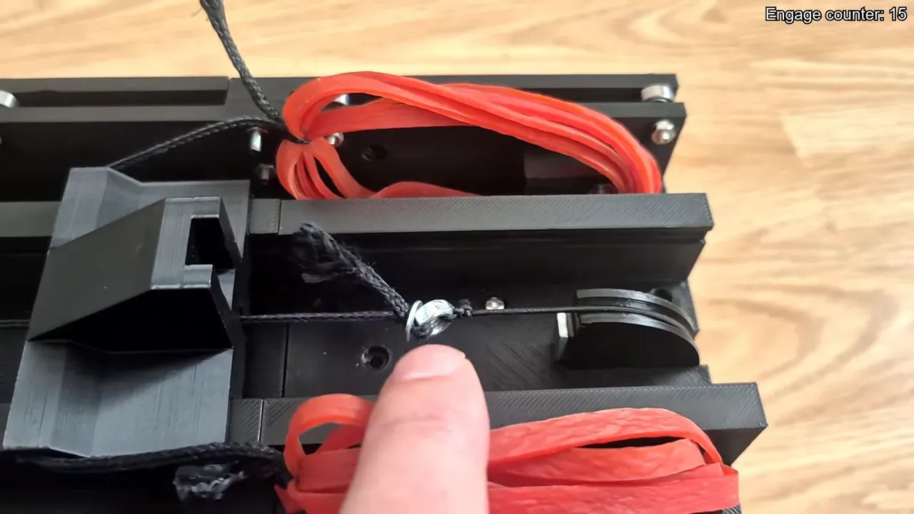 Top-down close shot of the Drone Slinger V2 showing the rear nut tied to the shuttle cable, the half-moon pulley and band stacks