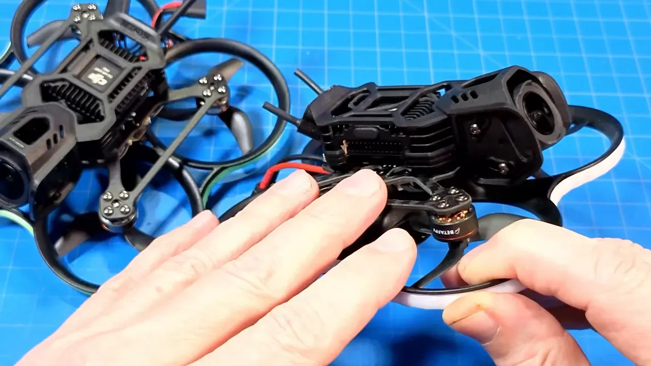 Close-up of a Pavo20 Pro II on a blue work mat with hands nearby, showing antenna stubs, daughterboard and wiring