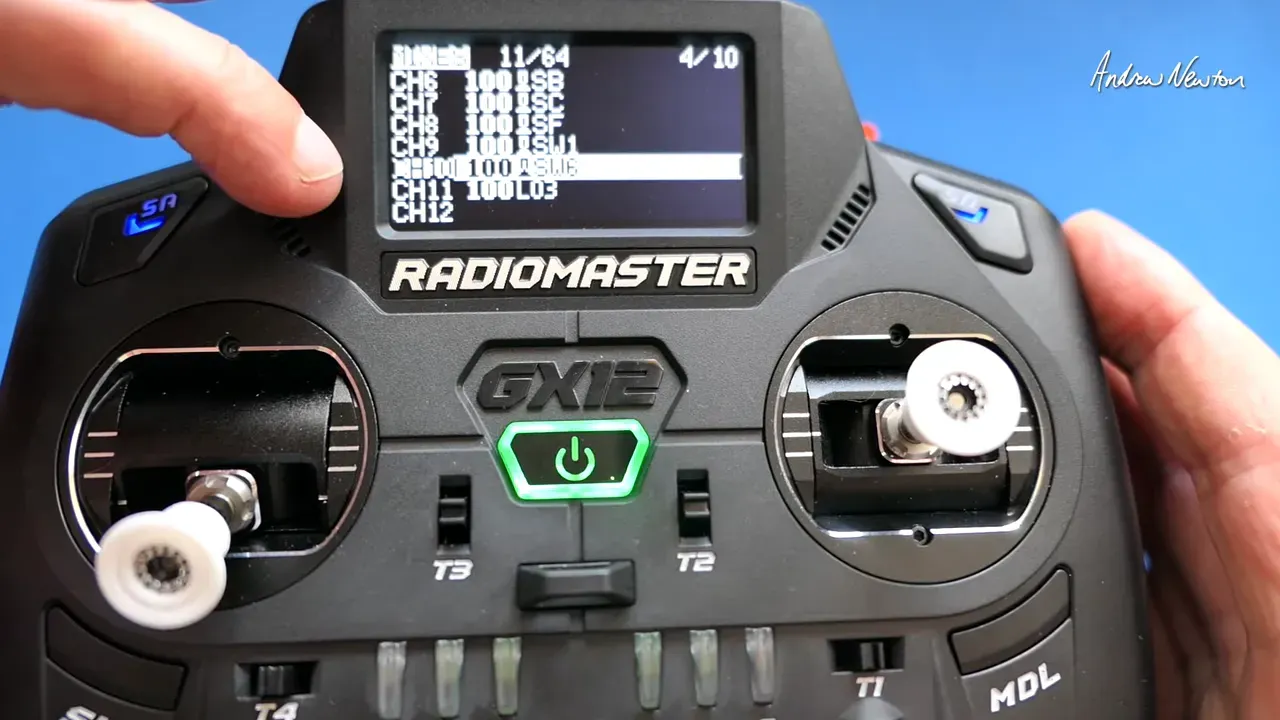 Radiomaster GX12 transmitter screen showing the MIXES menu with a highlighted channel entry and a hand pointing to the screen, clear view of sticks and front panel.