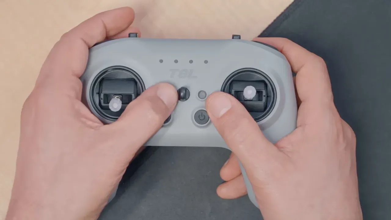 Overhead close-up of RadioMaster T8L controller showing gimbals, buttons and four-way trim rockers with hands holding the radio