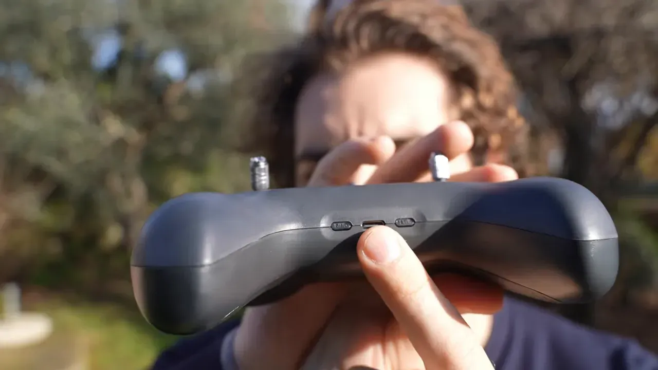 Close-up of Light Radio controller showing central bind button and USB-C port with finger pressing it