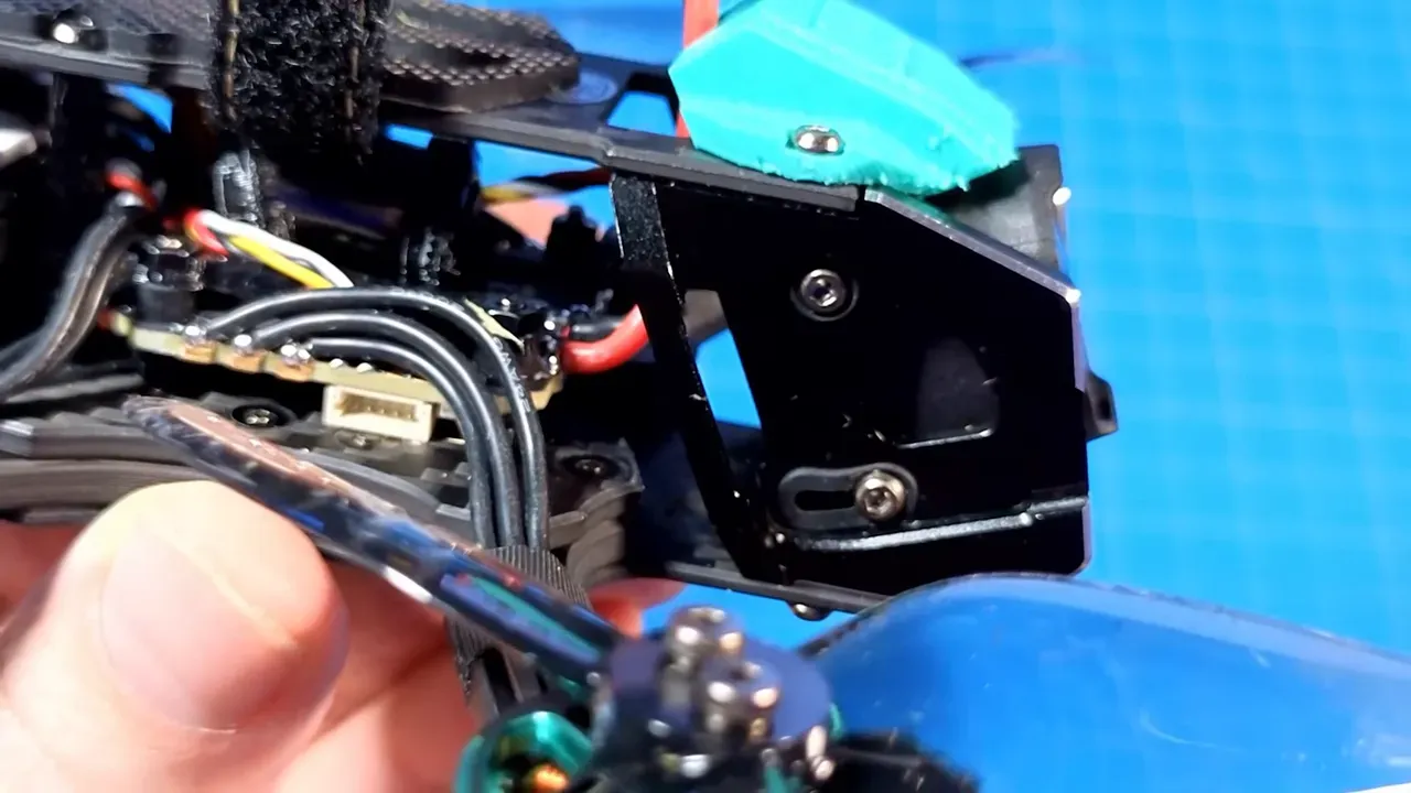 OasisFly35 front camera mount and metal bracket showing camera tilt limit, visible screws, wiring and a blue prop in the foreground.