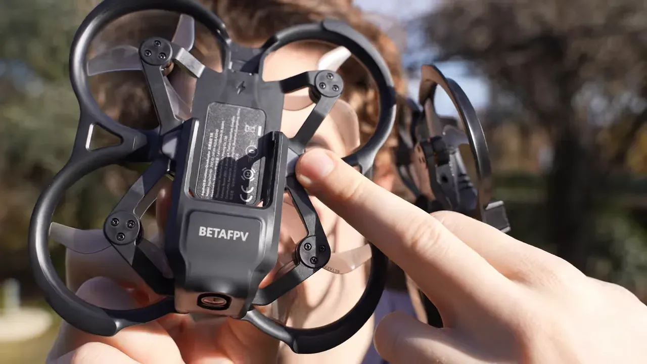 Close-up of BetaFPV Aquila20 HD frame with a finger pointing at the electronics and BETAFPV logo