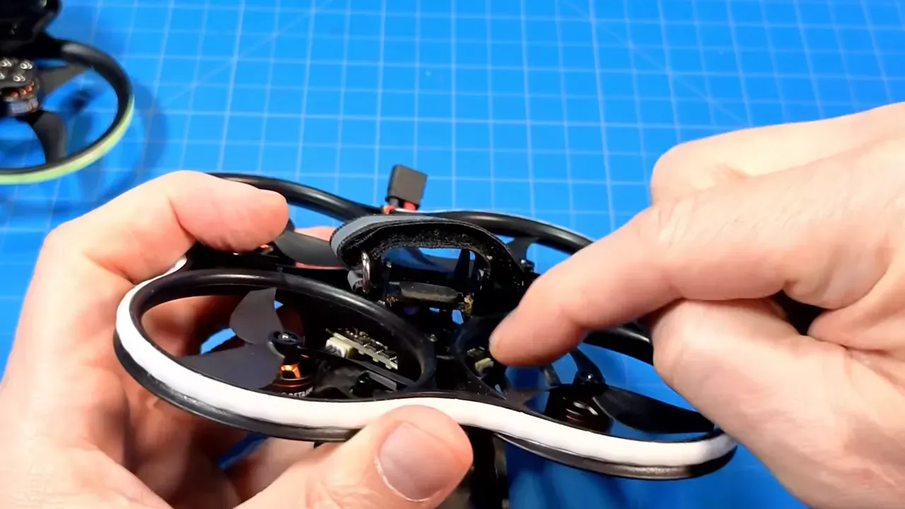 Hands pointing at the Pavo20 Pro II battery tray and plastic flanges ready for trimming or clipping