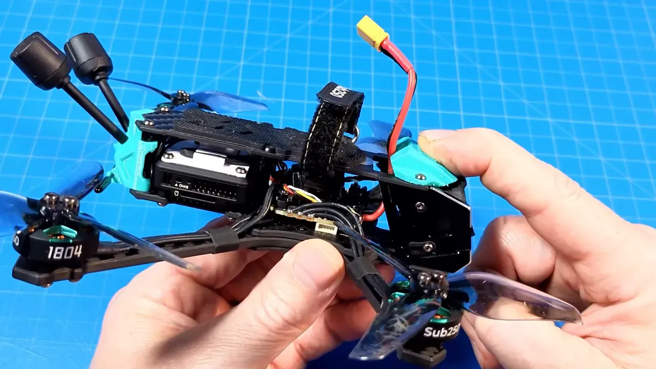 Clear view of OasisFly35 flight controller area, wiring and XT30 plug held in hands on a blue work mat