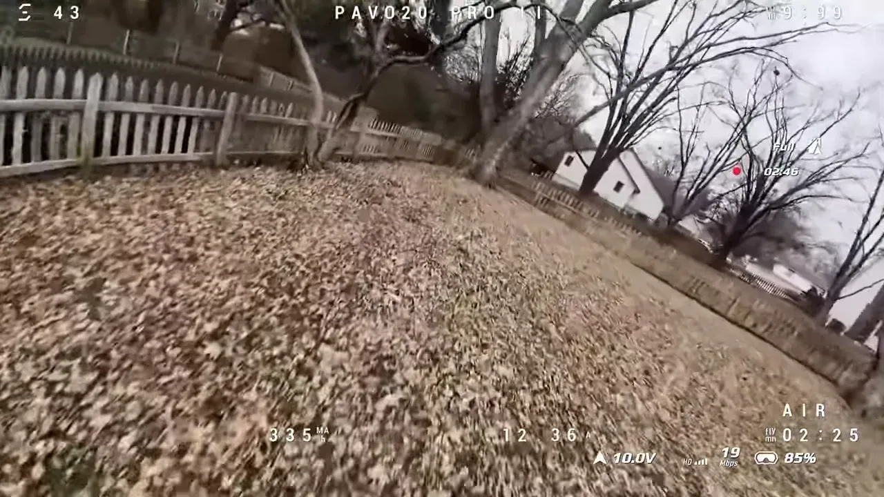 FPV view from a Pavo20 Pro II flying low along a backyard fence with a neighboring house visible, telemetry overlay