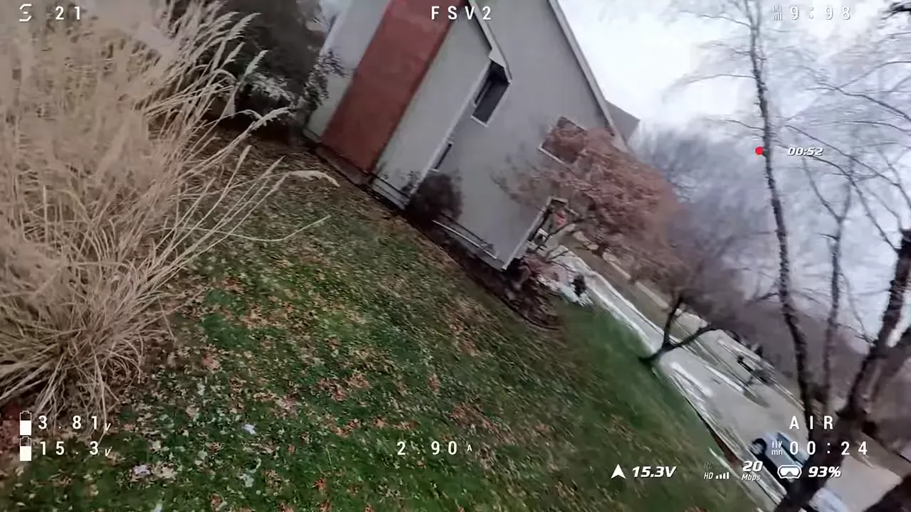 Tilted DVR frame from an O4 Lite flight showing a house, tall grass close to the lens and readable telemetry — demonstrates a constrained field of view.