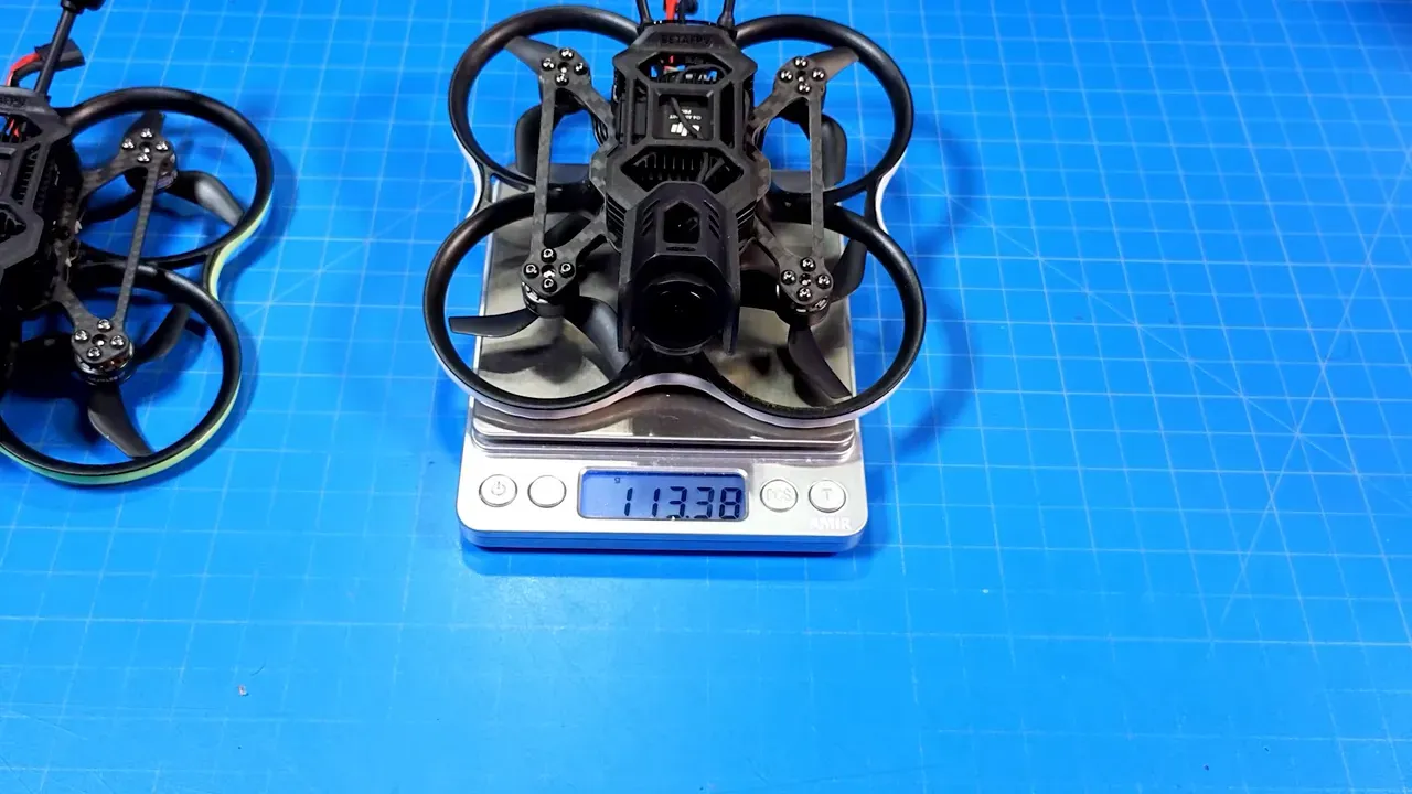 Pavo20 Pro II micro quad placed on a digital scale reading 113.38 grams on a blue work mat