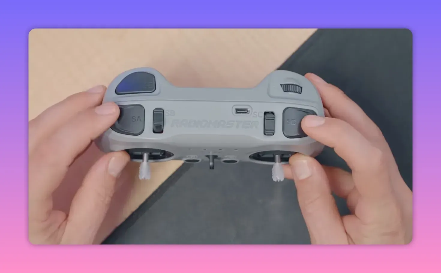 Top view of RadioMaster T8L showing labeled top switches (SA, SB, SC, SD), USB‑C port, ratcheted scroll wheel and gimbal sticks with hands interacting