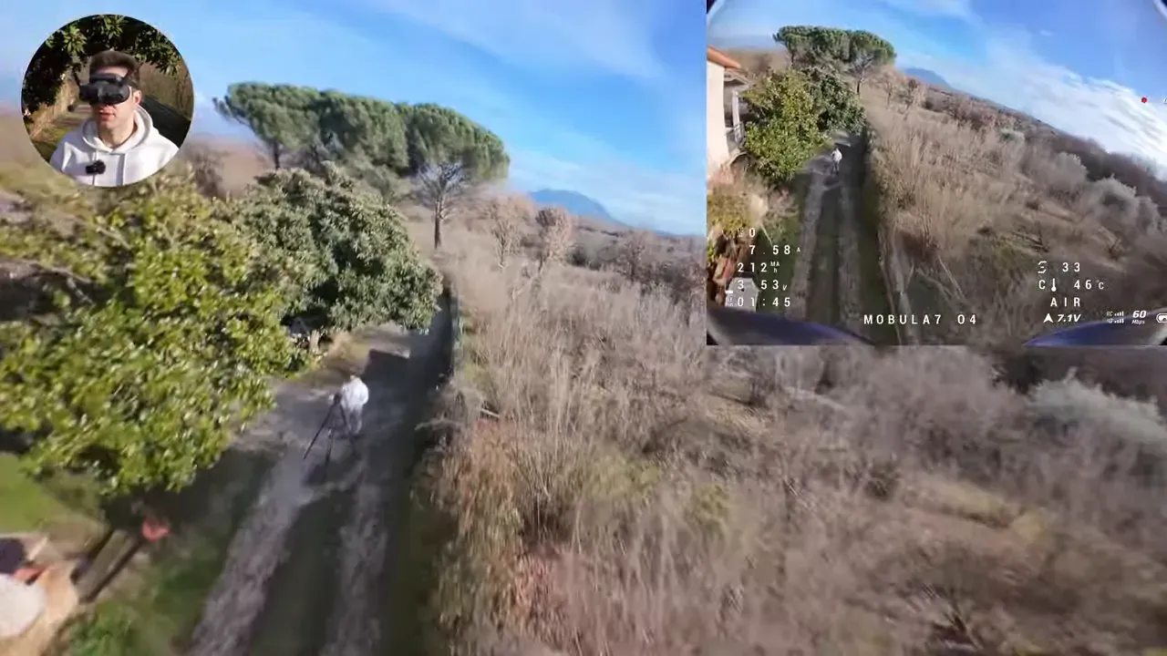 FPV camera view over a tree-lined track and yard with a presenter inset; ground path and a person with a tripod are visible below