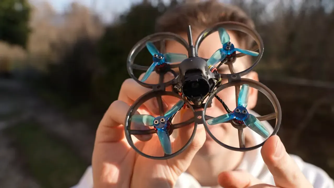 Close-up front view of Mobula 8 tiny whoop held by a person showing camera and prop guards