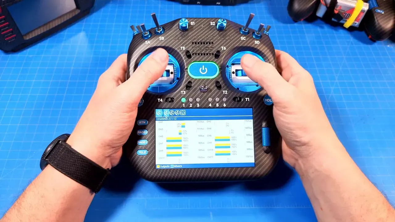 RadioMaster TX16S Mk3 Max centered with touchscreen displaying EdgeTX outputs page and hands on gimbals