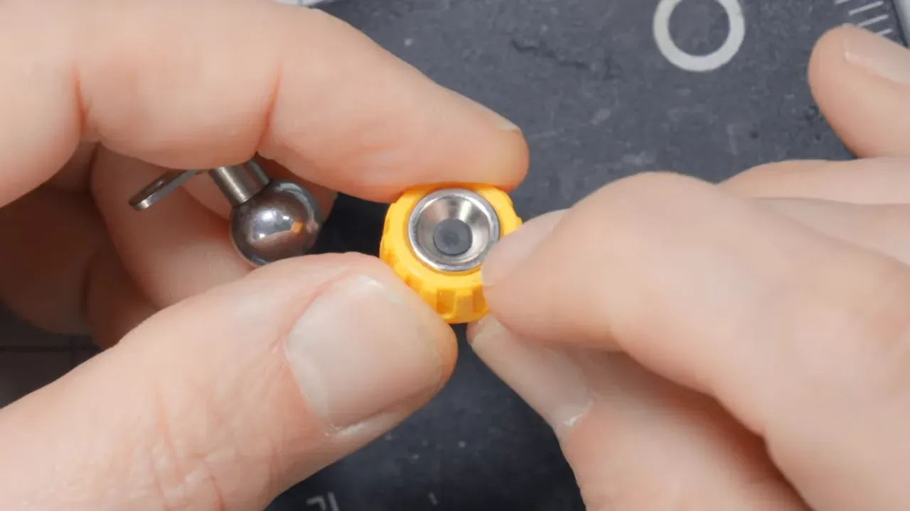 Close-up of hands holding a yellow magnetic base insert showing the exposed metal conductive ring inside the insert.