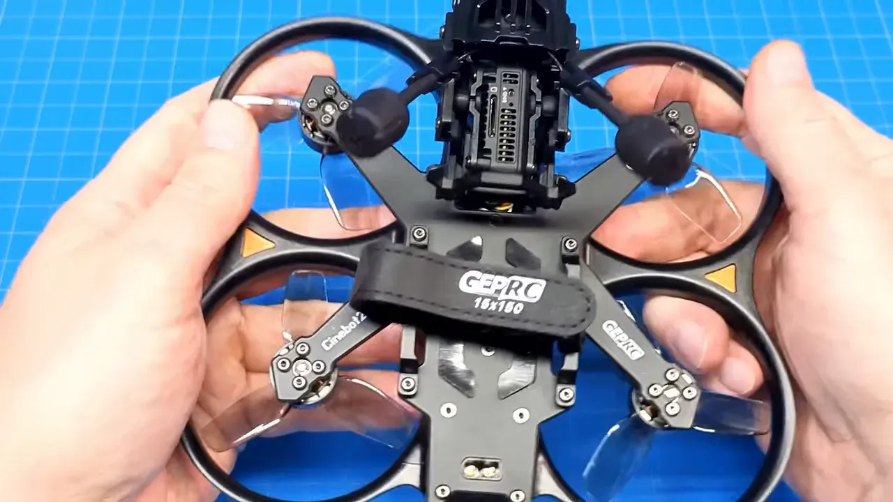 Top-down clear view of Cinebot25 V2 with prop guards, tri-blade props and GEPRC strap