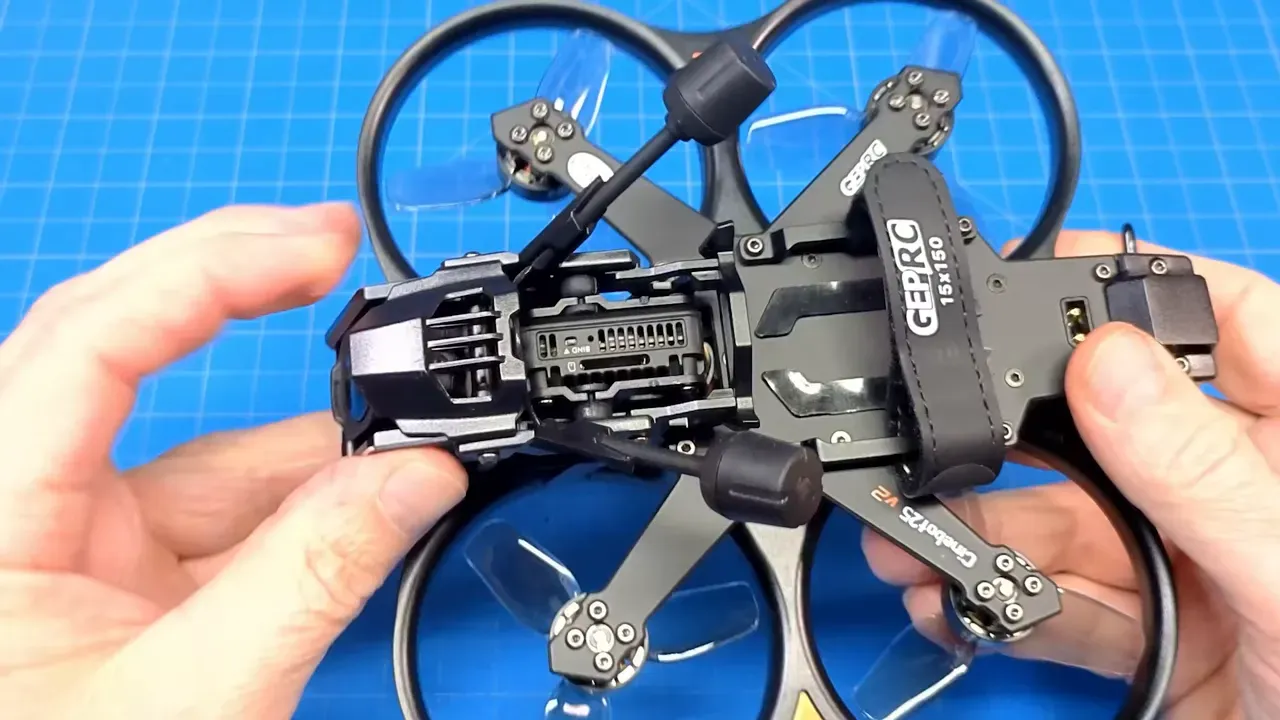 Top-down close view of Cinebot25 V2 camera module inside metal hood showing rubber mounts, hood vents and side adjustment screws