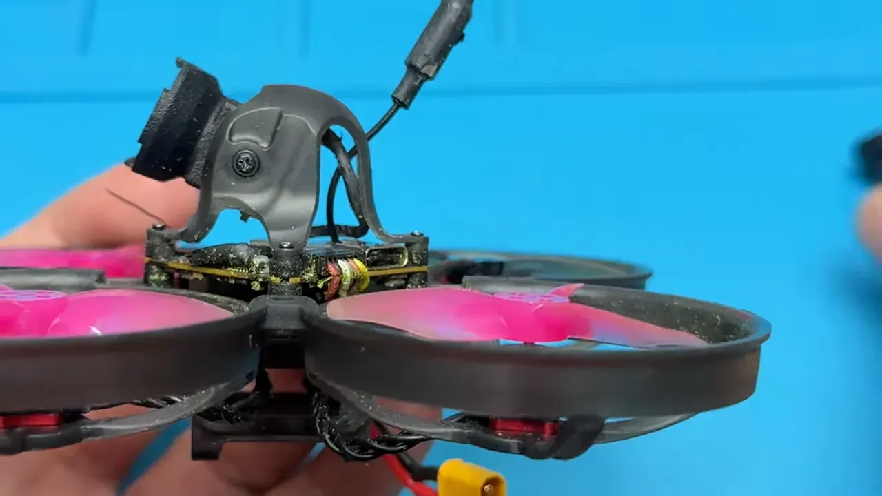 Mobula 8 cinewhoop with canopy and camera mount dislodged showing wiring and prop guards after a crash