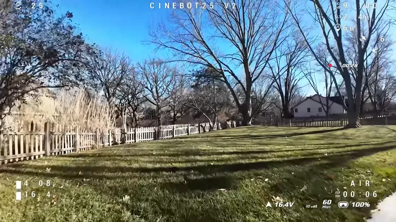 Cinebot25 V2 open-yard flight with trees, fence and visible telemetry showing satellite info