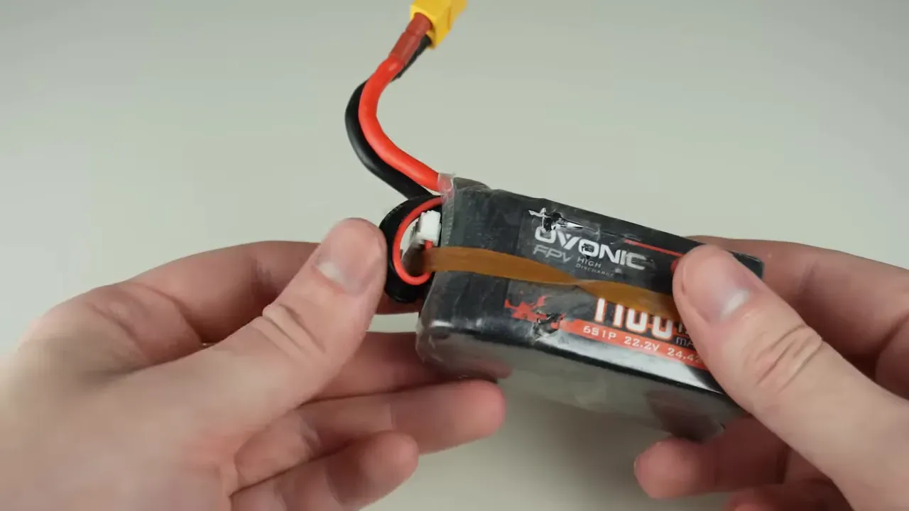 LiPo battery with balance connector tucked under pack held in place by a rubber band