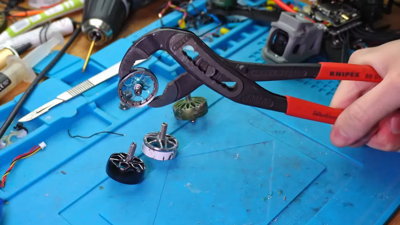 motor squeeze test showing pliers holding a brushless motor bell with other motors on a blue work mat