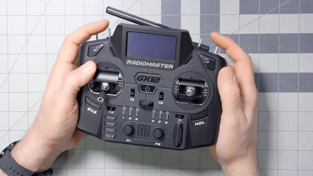 Frontal view of the workshop presenter wearing glasses and a 'Fly High' t-shirt with tools and desk behind