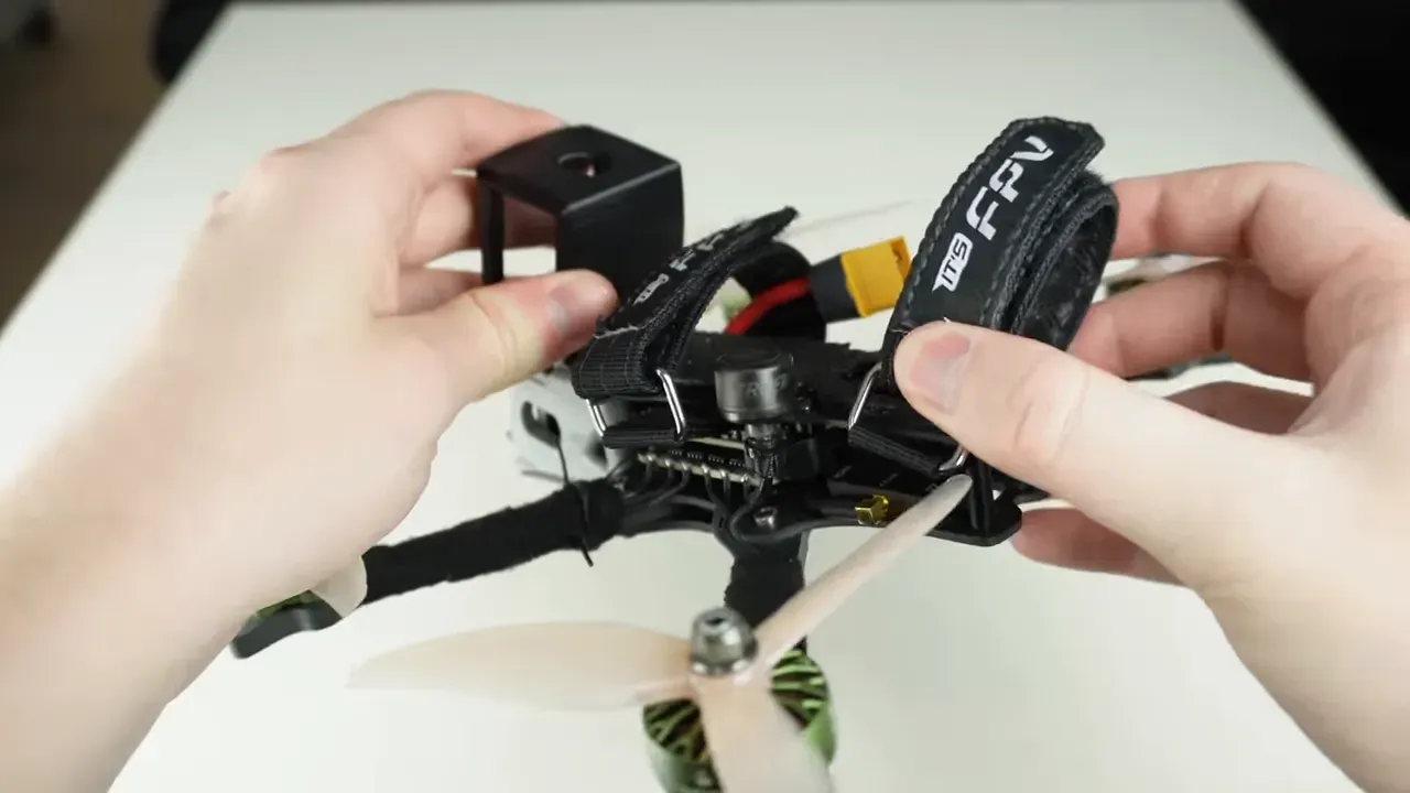 Top-centre view of FPV quad with battery straps, XT60 connector and electronics bay visible